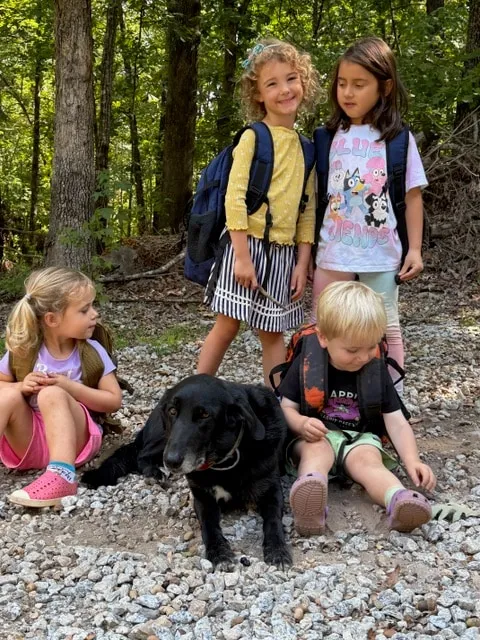 Children sitting on the gravel path with the school dog