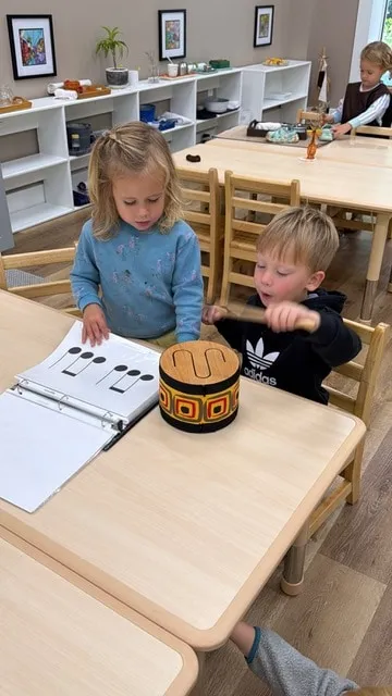 Children working with a music workbook at a classroom table