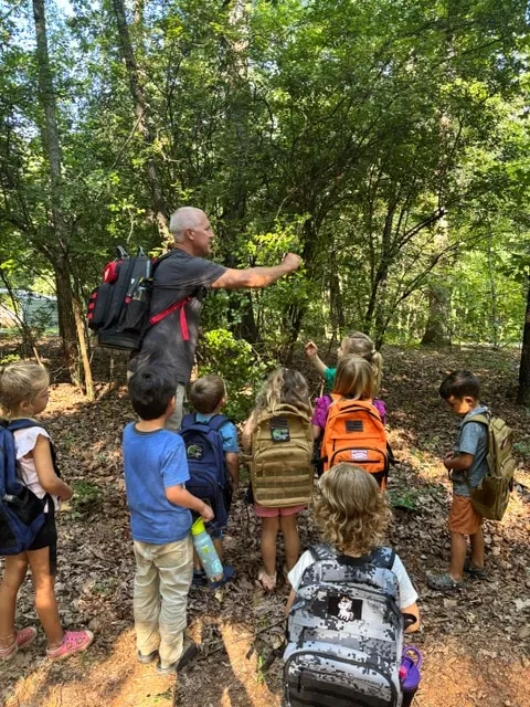 Teacher guiding children on a forest walk